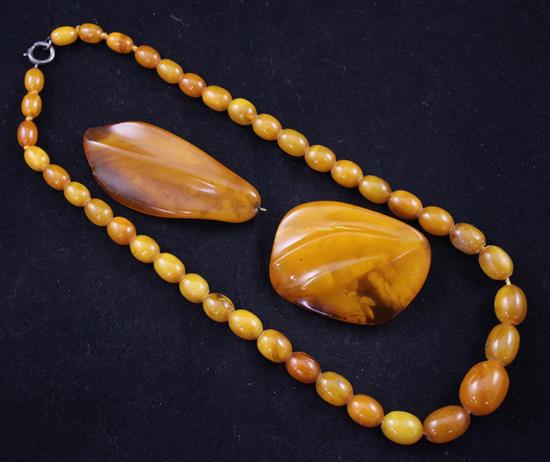 A single strand graduated oval amber bead necklace + 2 pendants/brooches